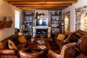 a living room with leather furniture and a fireplace at Kalderimi Country House in Mouresi