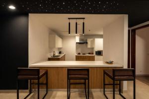 a kitchen with a counter and stools in it at Gold Crest Signature Boutique Apartments With City Views -DHA PHASE 4 LAHORE in Lahore