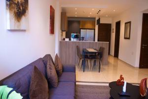 a living room with a blue couch and a kitchen at Sky View Condo at Solaris in Christiansborg