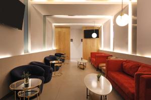 ein Wartezimmer mit einer roten Couch und Tischen in der Unterkunft Holiday Inn Monclova by IHG in Monclova
