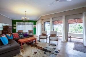 a living room with a couch and chairs and windows at Baleia Azul 24 in Ponta Mamoli