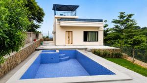 a villa with a swimming pool in front of a house at Mountain top farmhouse in Gurgaon