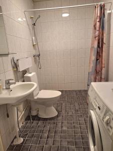a bathroom with a toilet and a sink and a washing machine at Private bedroom in Shared Apartment in Hämeenlinna