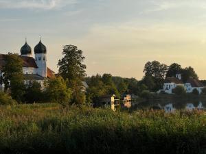 a building with a clock tower next to a lake at Das versteckte Nest in Seeon-Seebruck