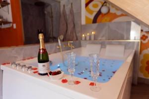 a bottle of wine and two glasses on a bath tub at La Seventies'room in Dijon