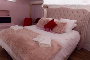 a white bed with a pink blanket and pillows at La Seventies'room in Dijon