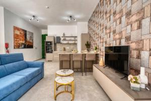 a living room with a blue couch and a kitchen at St Julian s Luxury Laura Apartments in Is-Swieqi