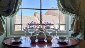 a table with wine glasses and china on it in front of a window at Downton I in Alnwick