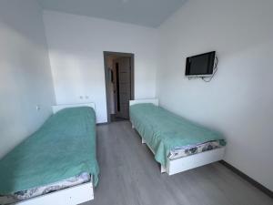 two beds in a room with a tv on the wall at Atabek in Bosteri +3 photos