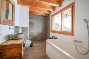 a bathroom with a tub and a sink and a window at Chalet t'Alpa in Bettmeralp