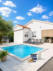 a swimming pool in front of a house at Villa Nevera in Omišalj