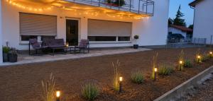 a patio with lights and chairs in front of a house at Apartment Illerblick in Dettingen an der Iller