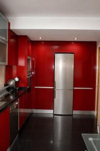 a kitchen with red walls and a stainless steel refrigerator at Casa do Pirata by GuestPro in Matosinhos +10 photos