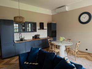 a kitchen with a couch and a table with a clock on the wall at Ośrodek Wypoczynkowo Sportowy Pod Żurawiem Ap 3 in Karolewo