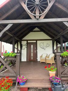 a wooden porch with two chairs and flowers at Ośrodek Wypoczynkowo Sportowy Pod Żurawiem Ap 3 in Karolewo