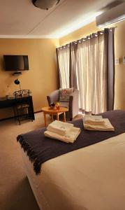 a hotel room with a bed with two towels on it at The Anne Guest House in Maseru