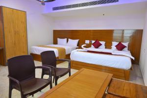 two beds in a room with two chairs and a table at VGN Convention Centre in Vāniyambādi