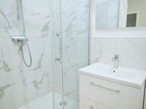 a white bathroom with a shower and a sink at Chez Alice 2 in Montbéliard