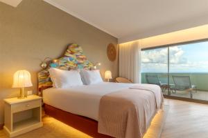 a bedroom with a large bed with a view of the ocean at Pestana Vila Lido Madeira Ocean Hotel in Funchal +40 photos