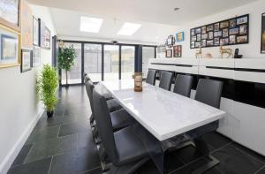 a dining room with a white table and chairs at Architectural Gem with Luxury Outdoor Kitchen in Chilham +15 photos