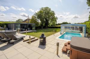 a backyard with a swimming pool and a house at Architectural Gem with Luxury Outdoor Kitchen in Chilham