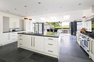 a kitchen with white cabinets and black counter tops at Architectural Gem with Luxury Outdoor Kitchen in Chilham