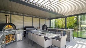 a patio with an outdoor kitchen with a fireplace at Architectural Gem with Luxury Outdoor Kitchen in Chilham