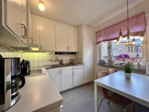 a kitchen with white cabinets and a table with chairs at Prinshöjden Apartments - Katrineholm Central in Katrineholm