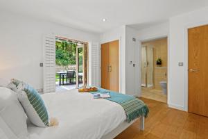 a white bedroom with a bed and a patio at House 29 in Looe +17 photos