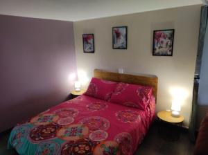 a bedroom with a bed with red sheets and two lamps at "La maison fleurie" Sud Vendée 85 in Avrillé