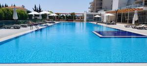 a large blue swimming pool with chairs and umbrellas at Healthy Apartments Abelia Residence in Iskele