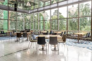 a cafeteria with tables and chairs and large windows at Scandic Rosendahl in Tampere