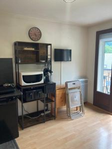 a living room with a microwave and a clock on the wall at Studio avec balcon Barèges in Barèges