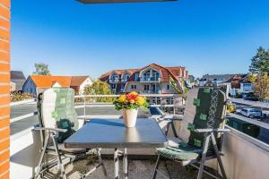 a table and chairs on a balcony with a vase of flowers at Haus Meeresgruß Muschel in Grömitz