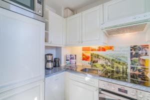 a kitchen with white cabinets and a sink at Haus Meeresgruß Muschel in Grömitz +11 photos