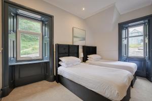 two beds in a room with two windows at Dalrigh House in Oban