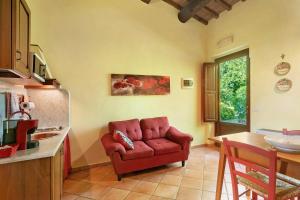 a living room with a red chair in a kitchen at Le Civette Country Resort with Pool in Bagno a Ripoli
