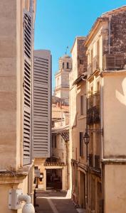 an alley with buildings and a clock tower in the background at Le Bel Angle in Arles