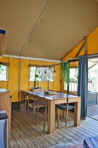 a dining room with a wooden table and chairs at Boeren glamping De Ruif De zilverberk in Stoutenburg +33 photos