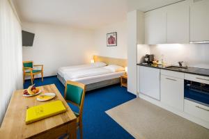 ein Zimmer mit einem Bett, einem Tisch und einer Küche in der Unterkunft Central Hotel Post in Chur