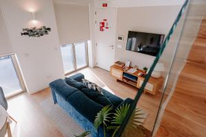 a living room with a blue couch and a tv at The Charming Loft in Esposende