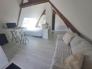 a living room with a bed and a desk with a laptop at Studio cosy in Saint-Pierre-en-Val