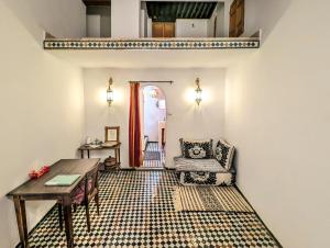 a living room with a table and a chair at Rooms in Dar Drouj, a special 14th century house Riad in Fez