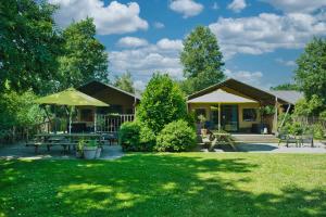 a campsite with picnic tables and umbrellas in a park at Boeren glamping De Ruif De zilverberk in Stoutenburg
