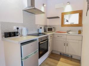a small kitchen with white cabinets and a sink at Snowy Owl Barn in Shipdham