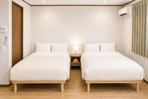 two beds in a room with a lamp on a table at Tokyo Grand House in Akishima