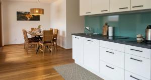 a kitchen with white cabinets and a dining room with a table at Moderne Ferienwohnung im Bregenzerwald in Au im Bregenzerwald