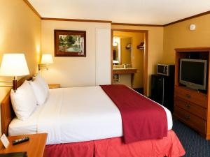 a hotel room with a bed and a television at Sunrise Inn - Bradenton in Bradenton
