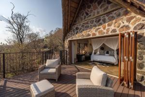 a room with a bed and chairs on a patio at Magari Safari Lodge in Vaalwater