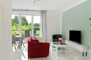a living room with a red chair and a table at Gemütliche Wohnung mit Terrasse im Grünen in Bienenbüttel